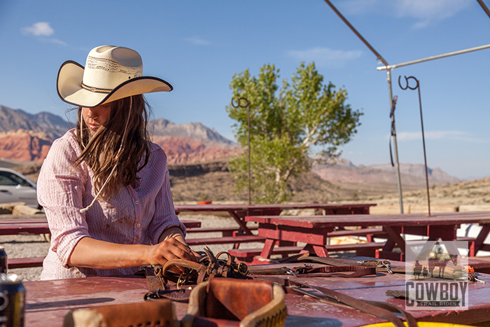 Cowboy Trail Rides - Wrangler repairs saddles in camp
